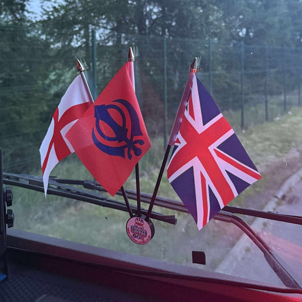 Flags on a car dashboard with a road and trees in the background